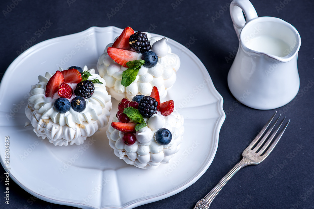 Delicate white meringues with fresh berries on the plate. Dessert Pavlova close-up. Wedding cake. Delicate white meringues with fresh berries on the plate. Dessert Pavlova close-up. Wedding cake.