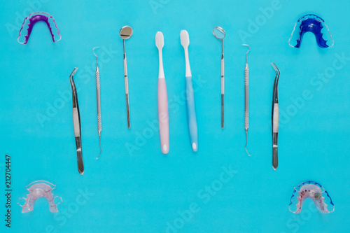 Dental tools and retainer orthodontic appliance on the blue background, flat lay, top vipw.
