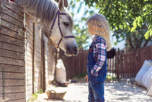 Canvas Print side view of kid looking at white horse at farm