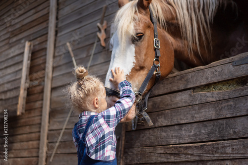 preteen kid palming big horse at farm photo