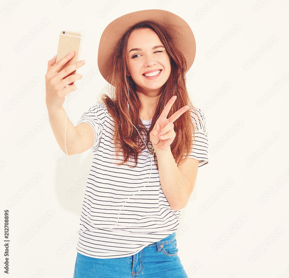 Portrait of a pretty girl in summer hipster clothes taking a selfie isolated on white background. Winking and showing peace sign Portrait of a pretty girl in summer hipster clothes taking a selfie isolated on white background. Winking and showing peace sign