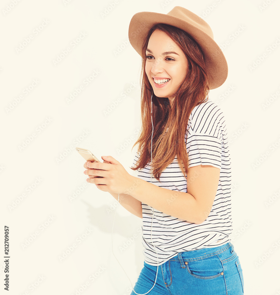 beautiful smiling brunette woman girl in casual hipster summer clothes with no makeup in brown hat listening music in smartphone with headphones. isolated on white. Dancing beautiful smiling brunette woman girl in casual hipster summer clothes with no makeup in brown hat listening music in smartphone with headphones. isolated on white. Dancing