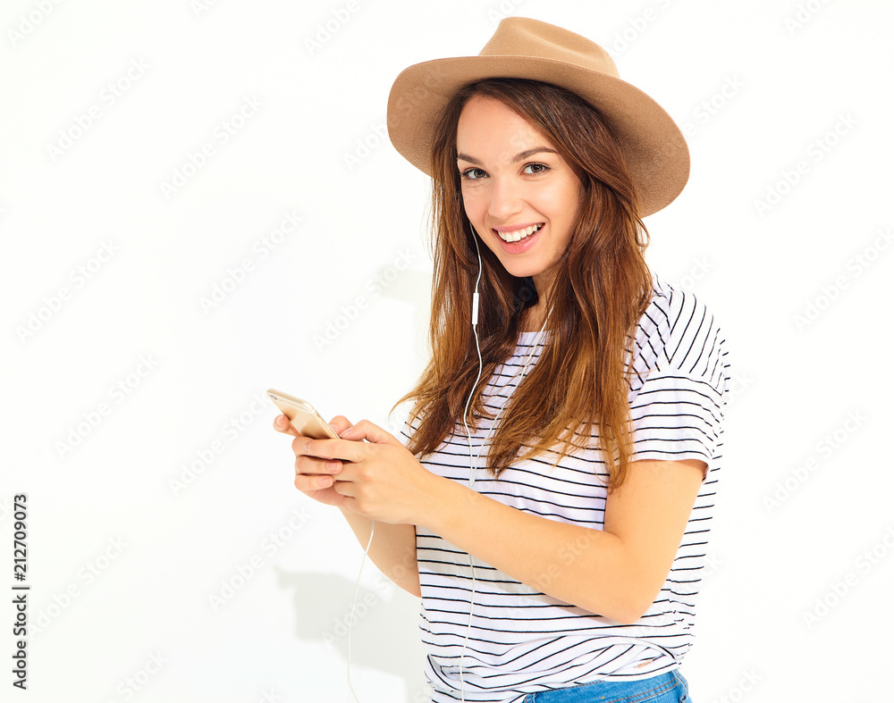 beautiful girl in casual hipster summer clothes with no makeup in brown hat listening music in smartphone with headphones isolated on white. Dancing beautiful girl in casual hipster summer clothes with no makeup in brown hat listening music in smartphone with headphones isolated on white. Dancing