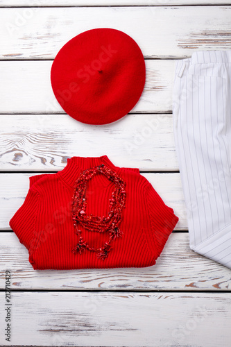 Folded red sweater and berete hat. Vertical cropped view. photo