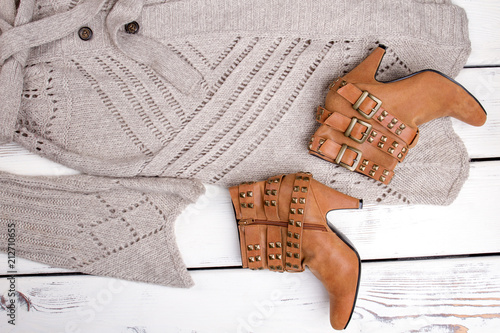 Flat lay close up brown heel boots and woolen coat. Brigh wooden background. photo