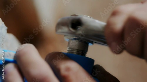 Worker's hands screwing the nut with a large wrench close-up