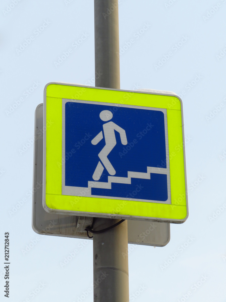City sign of the underpass. Coming down the stairs man on a blue background in a yellow frame. City sign of the underpass. Coming down the stairs man on a blue background in a yellow frame.