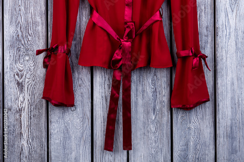 Bottom of bowed red silk coat. Top view, wooden background.