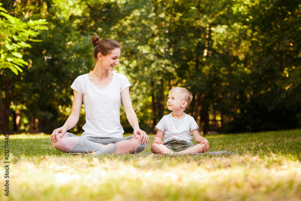 Mom and son are practicing yoga in the park. Mom and son are practicing yoga in the park.