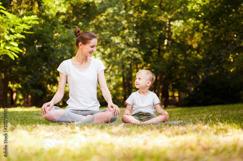 Mom and son are practicing yoga in the park. © galina_kovalenko