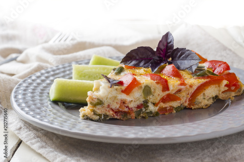 Omelet serving with vegetables on a plate on a white wooden table