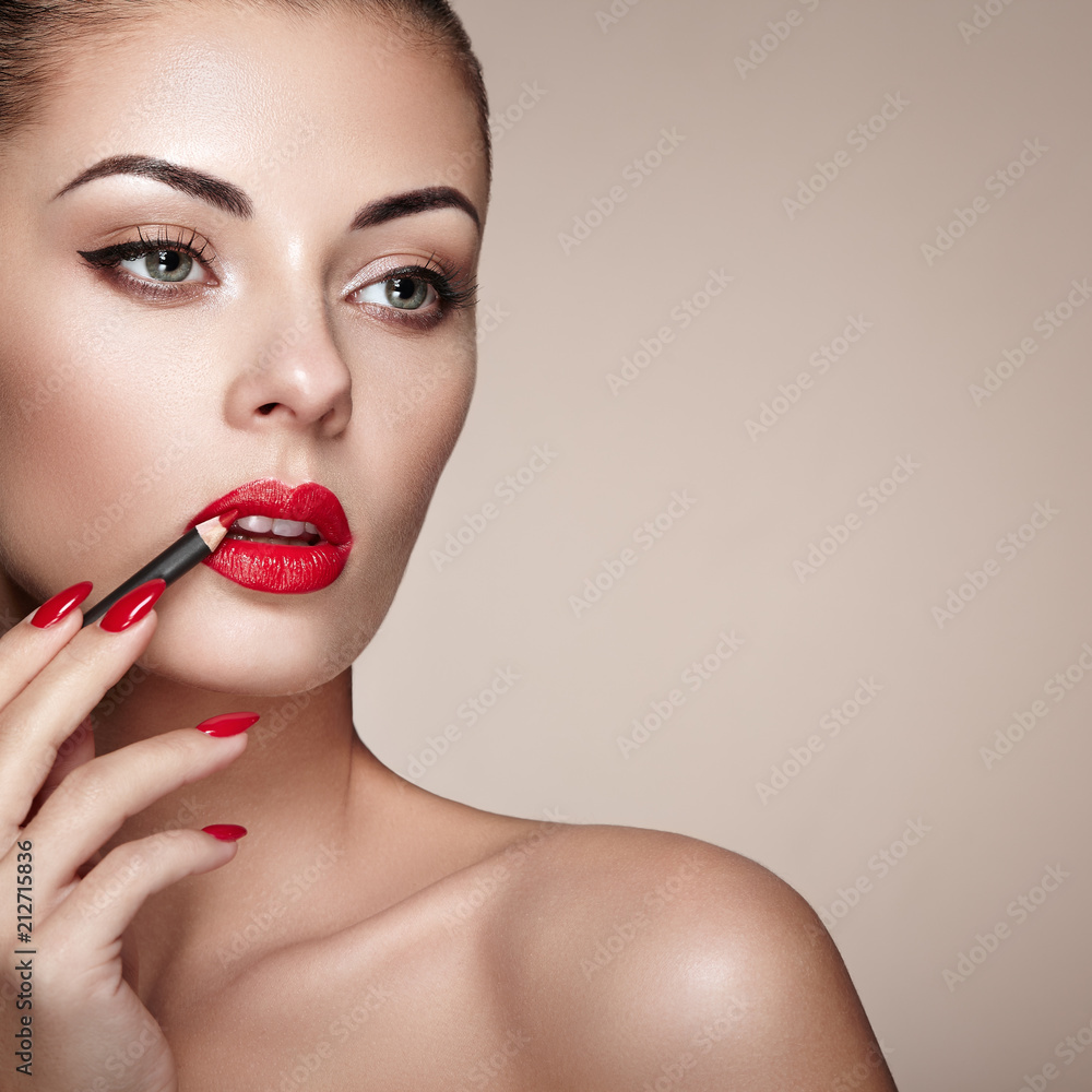 Beautiful Woman paints Lips with Lipstick. Beautiful Woman Face. Makeup detail. Beauty Model with Perfect Skin. Red Lips and Nails Manicure Beautiful Woman paints Lips with Lipstick. Beautiful Woman Face. Makeup detail. Beauty Model with Perfect Skin. Red Lips and Nails Manicure