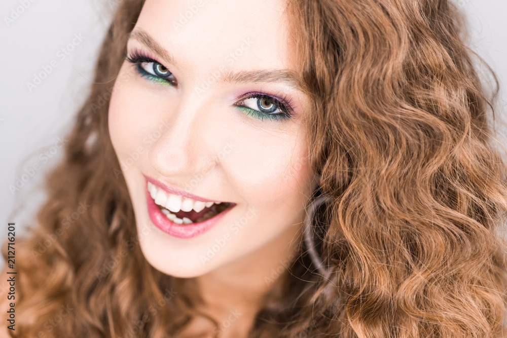portrait beautiful young blonde curly girl posing in the studio with professional make-up and open tooth smile portrait beautiful young blonde curly girl posing in the studio with professional make-up and open tooth smile