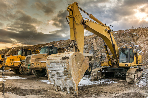 Excavator and trucks realizing construction works of a road