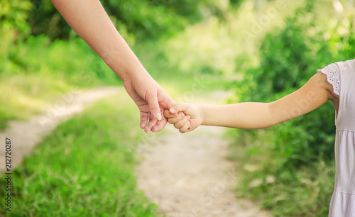 Mom and daughter are walking along the road holding hands. Selective focus. photo