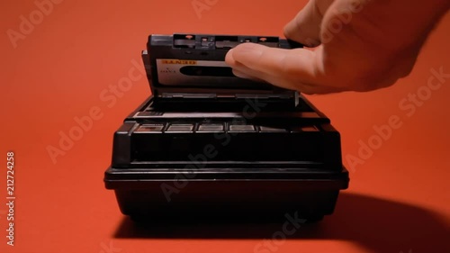 Inserting and removing an audio cassette from a retro vintage player. Medium shot on a red background.
 photo