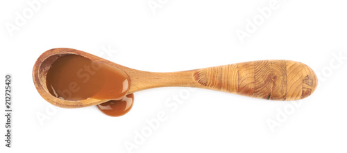Wooden spoon of caramel sauce isolated