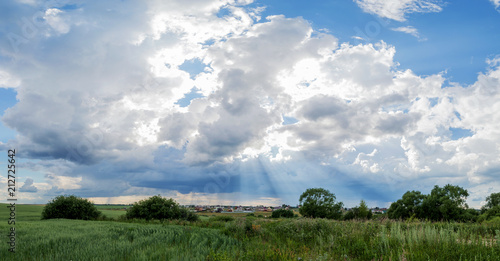 Blue sky with cumulus white clouds over a green field in summer