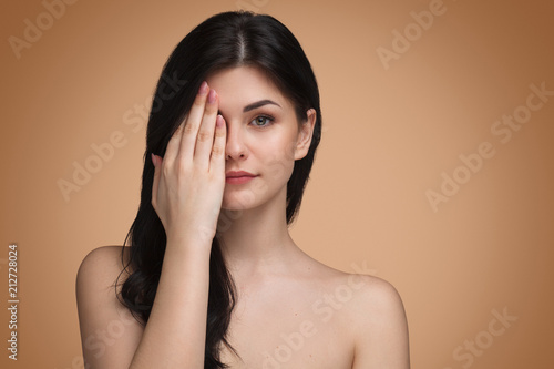Cute woman covering eye with hand