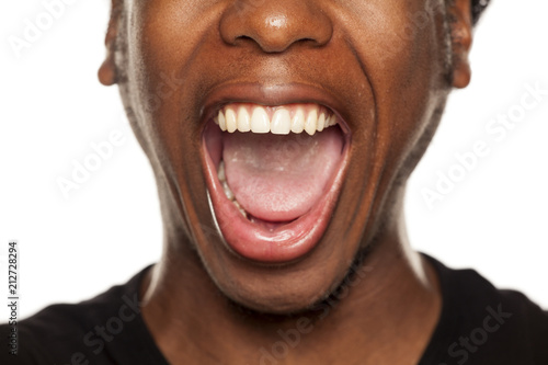 Open mouth closeup of young black african american guy on white background photo