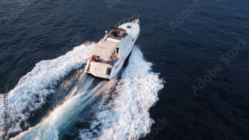 Aerial birds eye view from drone of boat cruising in high speed in turquoise water, island of Mykonos, Cyclades, Greece © aerial-drone