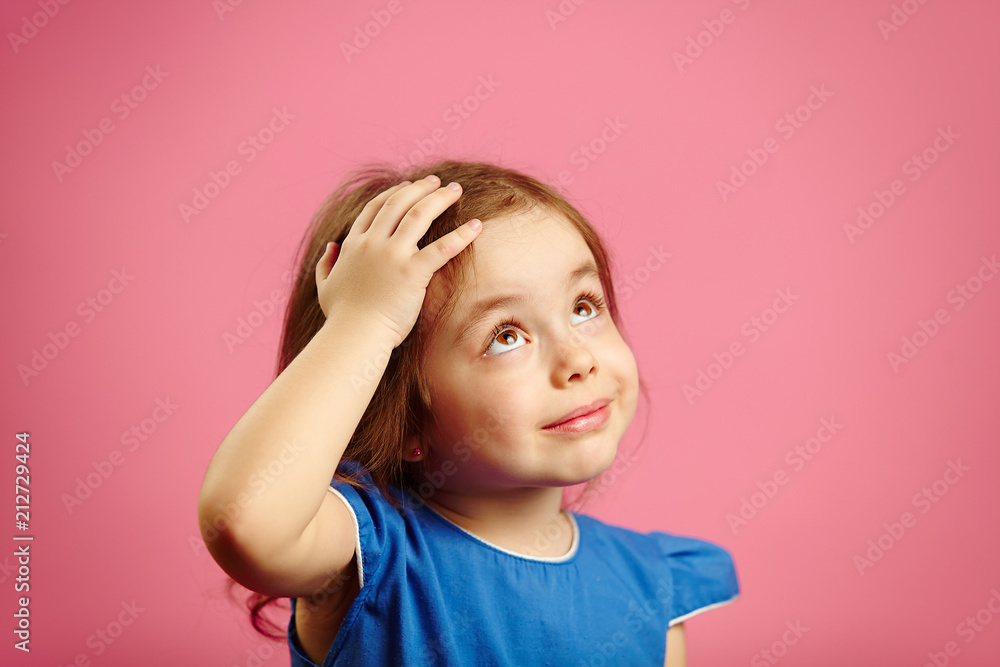 Cute children girl put her hand to head and looks up Cute children girl put her hand to head and looks up