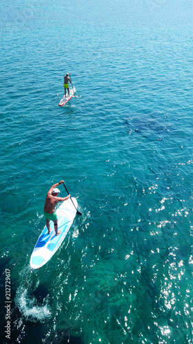 Aerial drone photo of 2 men practicing SUP or Stand Up Paddle board in tropical caribbean clear open sea