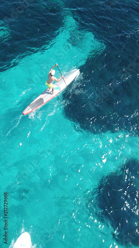 Aerial drone bird s eye view of man exercising sup board in turquoise tropical clear waters