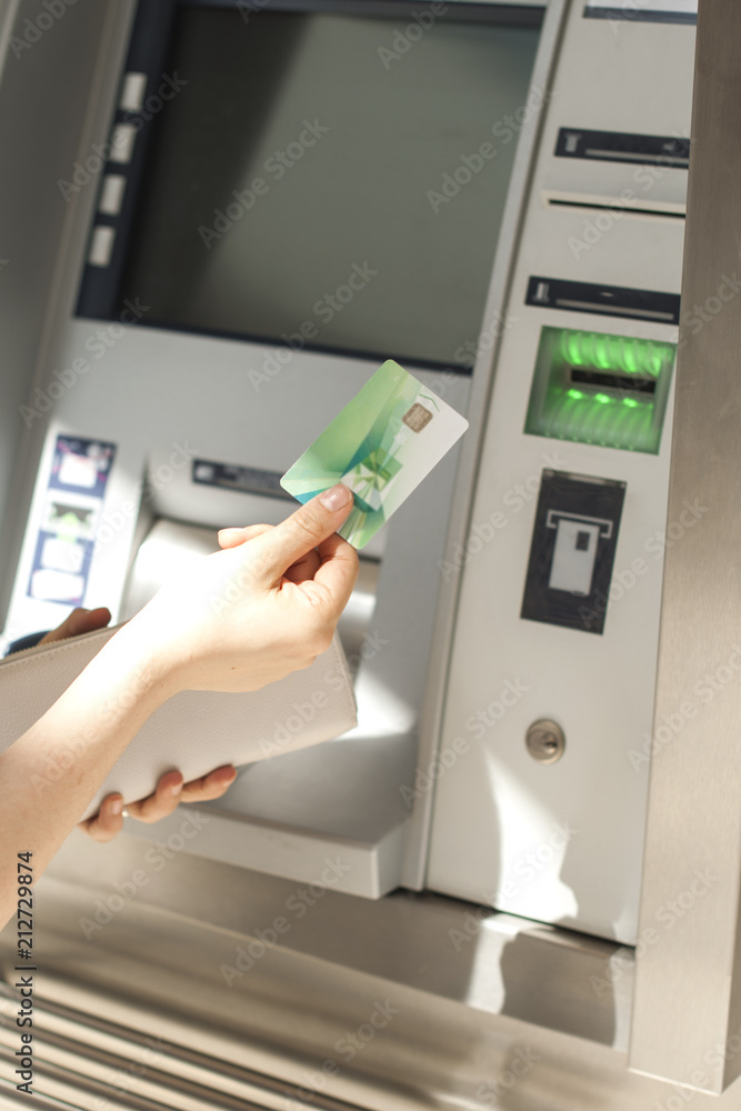A woman uses a credit card at an ATM on the street. Operation with money. Payment. Copy space. A woman uses a credit card at an ATM on the street. Operation with money. Payment. Copy space.