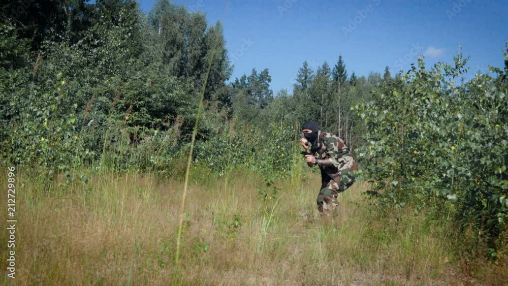 Soldier with gun talking on two way radio in forest Soldier with gun talking on two way radio in forest