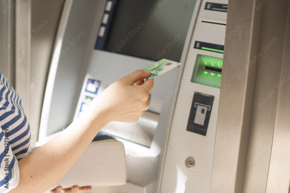 A woman uses a credit card at an ATM on the street. Operation with money. Payment. Copy space. A woman uses a credit card at an ATM on the street. Operation with money. Payment. Copy space.