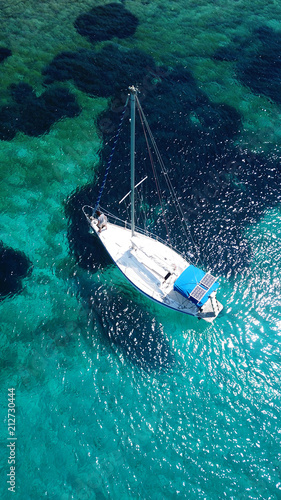 Aerial drone birds eye view of sail boat docked in an Ionian island with crystal clear emerald sea, Greece