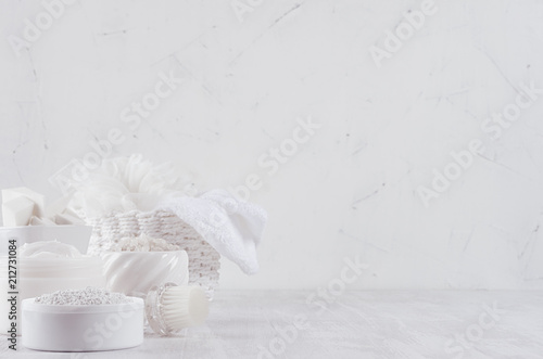 White spa cosmetics products and light bath accessories on white wood background, interior, copy space.