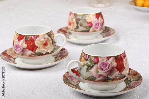 Three porcelain teacups with floral pattern on a white tablecloth