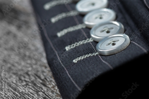 Bespoke jacket..Close up detail of sleeve  buttons and stitching for custom made jacket on old wooden table, professional tailor concept. photo