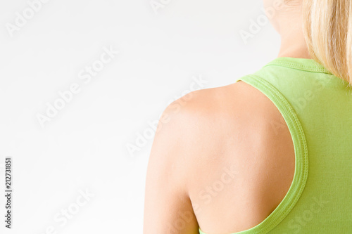 Young, sporty woman's back. Green sportswear. Ready for activities. Copy space. Empty place for text on light gray background.