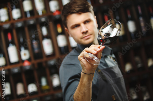 Bokal of red wine on background, male sommelier appreciating drink