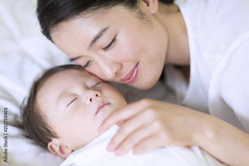 眠っている赤ちゃんに頬を寄せる母親 眠っている赤ちゃんに頬を寄せる母親