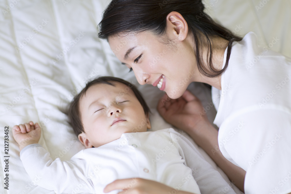 眠っている赤ちゃんを見て微笑む母親 眠っている赤ちゃんを見て微笑む母親