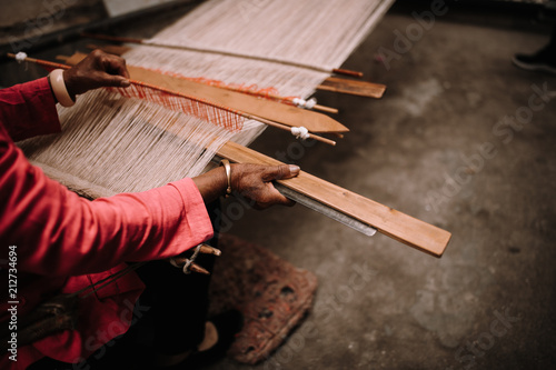 Woman weaving at loom with shuttle at workshop