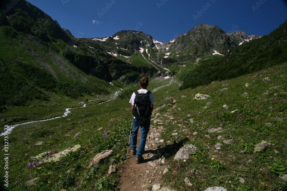 Tourist with a backpack is on the trail to the mountain pass, Arkhyz.
