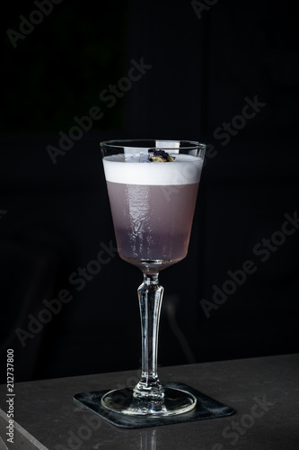 purple drink with blueberries in a glass on a high leg with ice