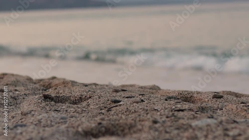Beautiful Beach and Sea at Sunrise. Close up sand and stones. Waves out of focus in backround