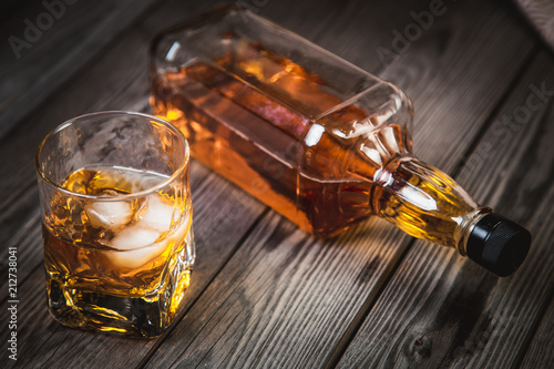 glass of whiskey and a bottle of whiskey on a wooden background