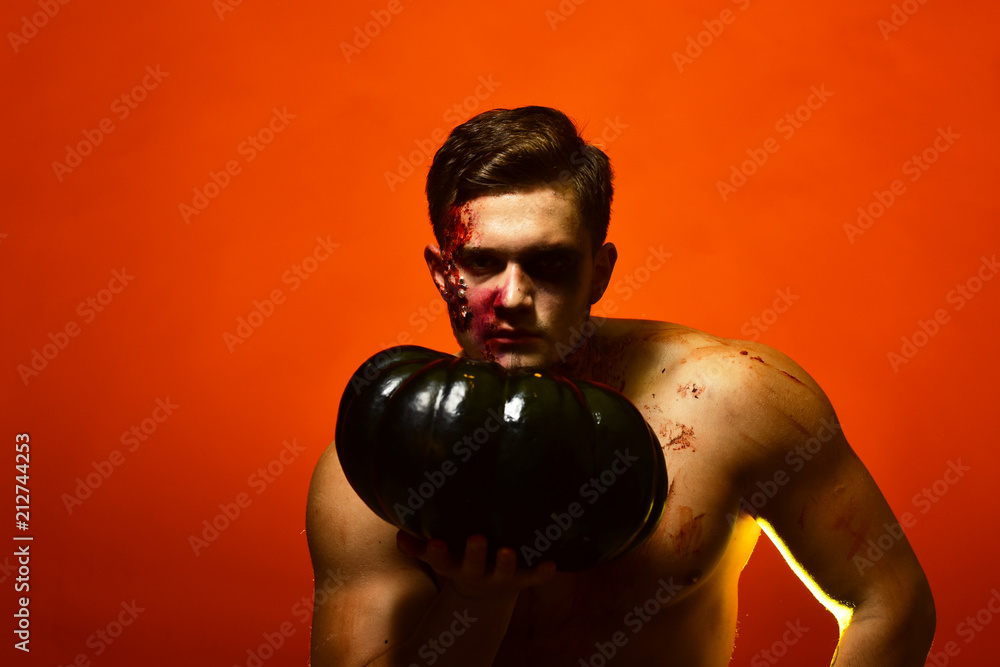 Macho with torso holds pumpkin. Man with serious face