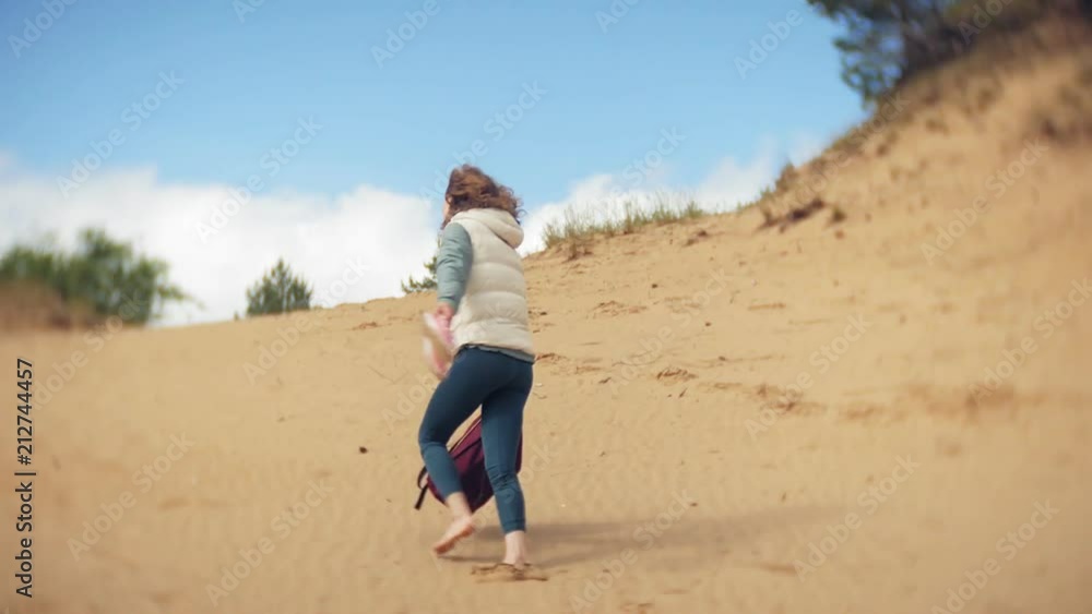 A woman is walking along the sand on the beach by the sea, enjoying life A woman is walking along the sand on the beach by the sea, enjoying life