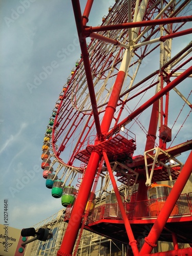 A bottom-up view of a red ferris wheel during golden hour