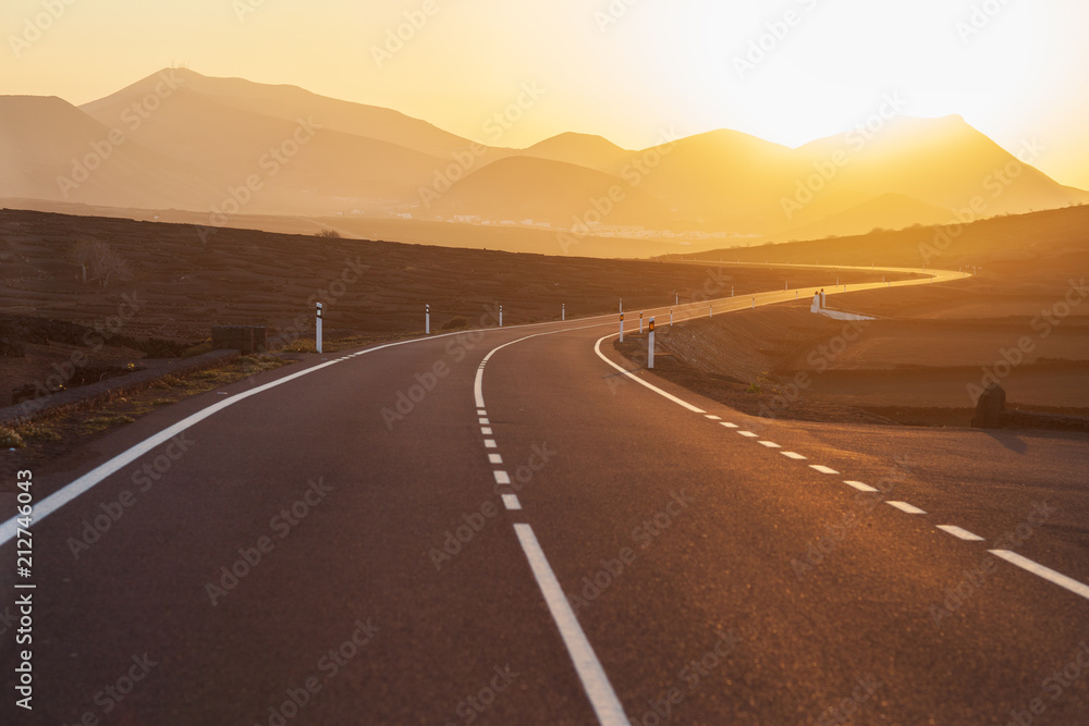 Asphalt road to mountain on sunset