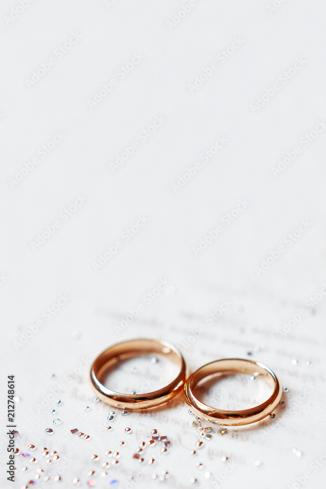 Golden wedding rings on paper invitation with shiny rhinestones. Wedding details, symbol of love and marriage. Golden wedding rings on paper invitation with shiny rhinestones. Wedding details, symbol of love and marriage.