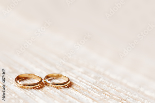 Golden wedding rings on beige fabric background. Wedding details, symbol of love and marriage.